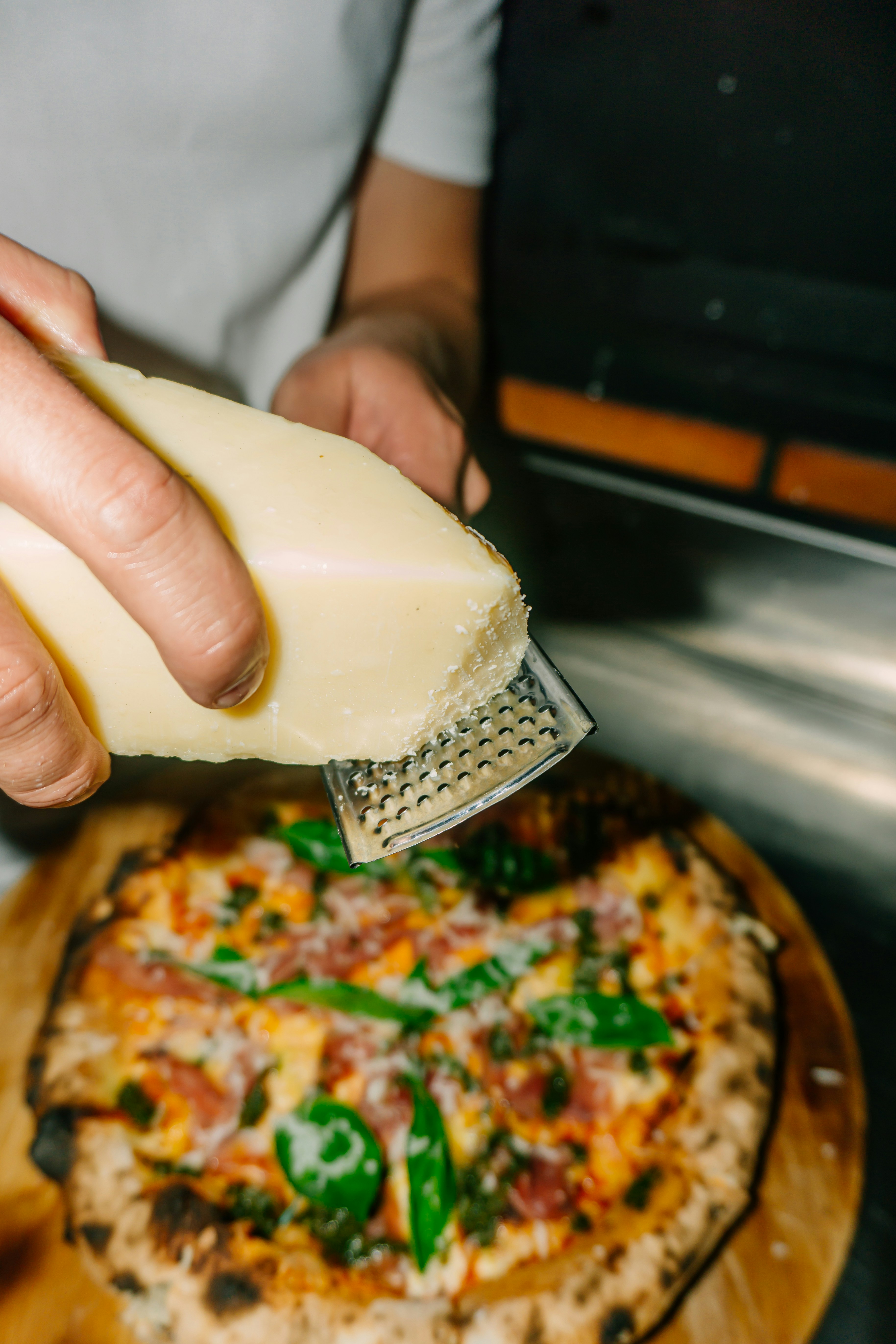 Una persona rallando queso encima de una pizza