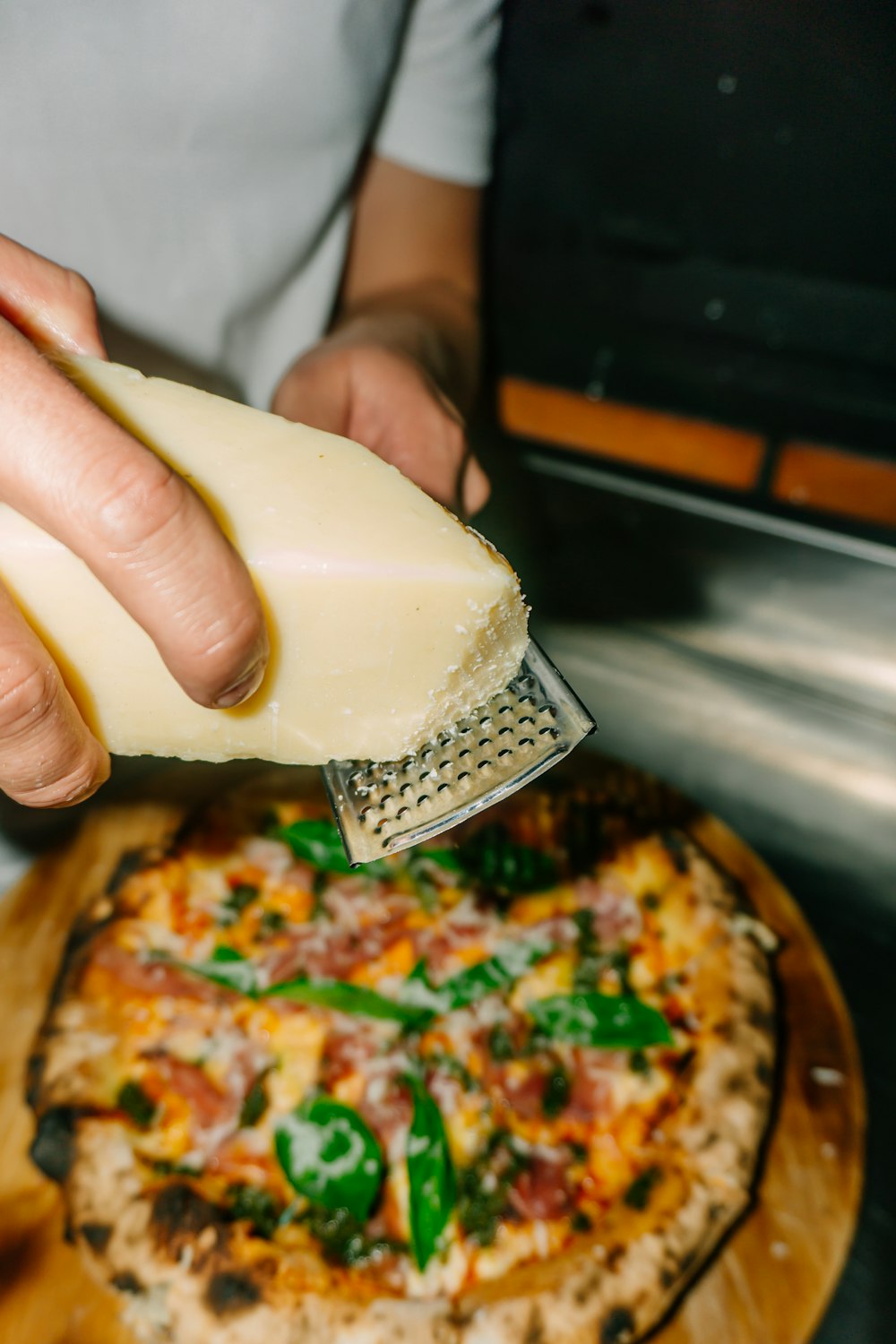 a person grating cheese on top of a pizza