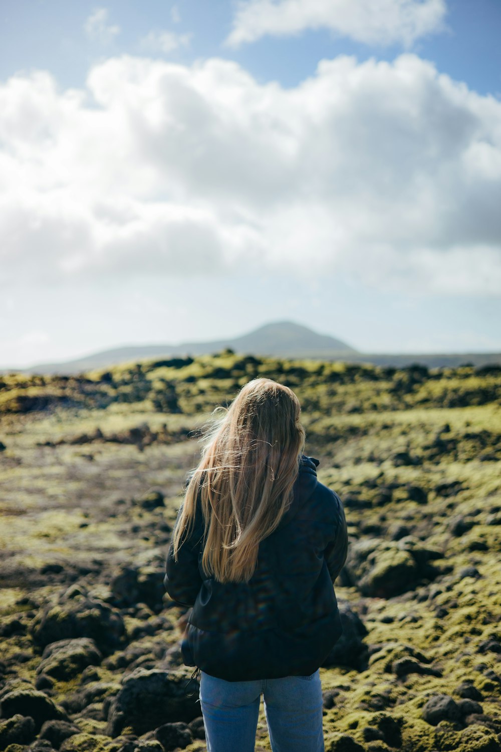 a woman in a black jacket is standing in a field