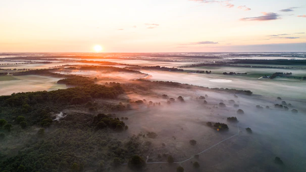 A wide-angle photo capturing a serene landscape with soft morning light and mist.