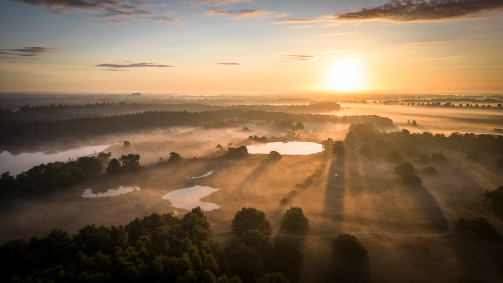 the sun is setting over a foggy field