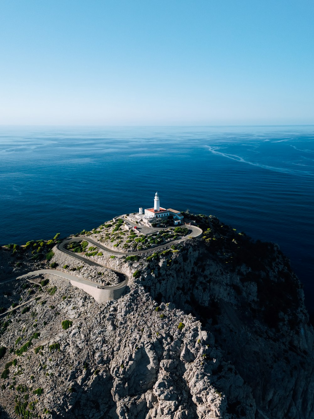 a lighthouse on a rocky outcropping in the middle of the ocean