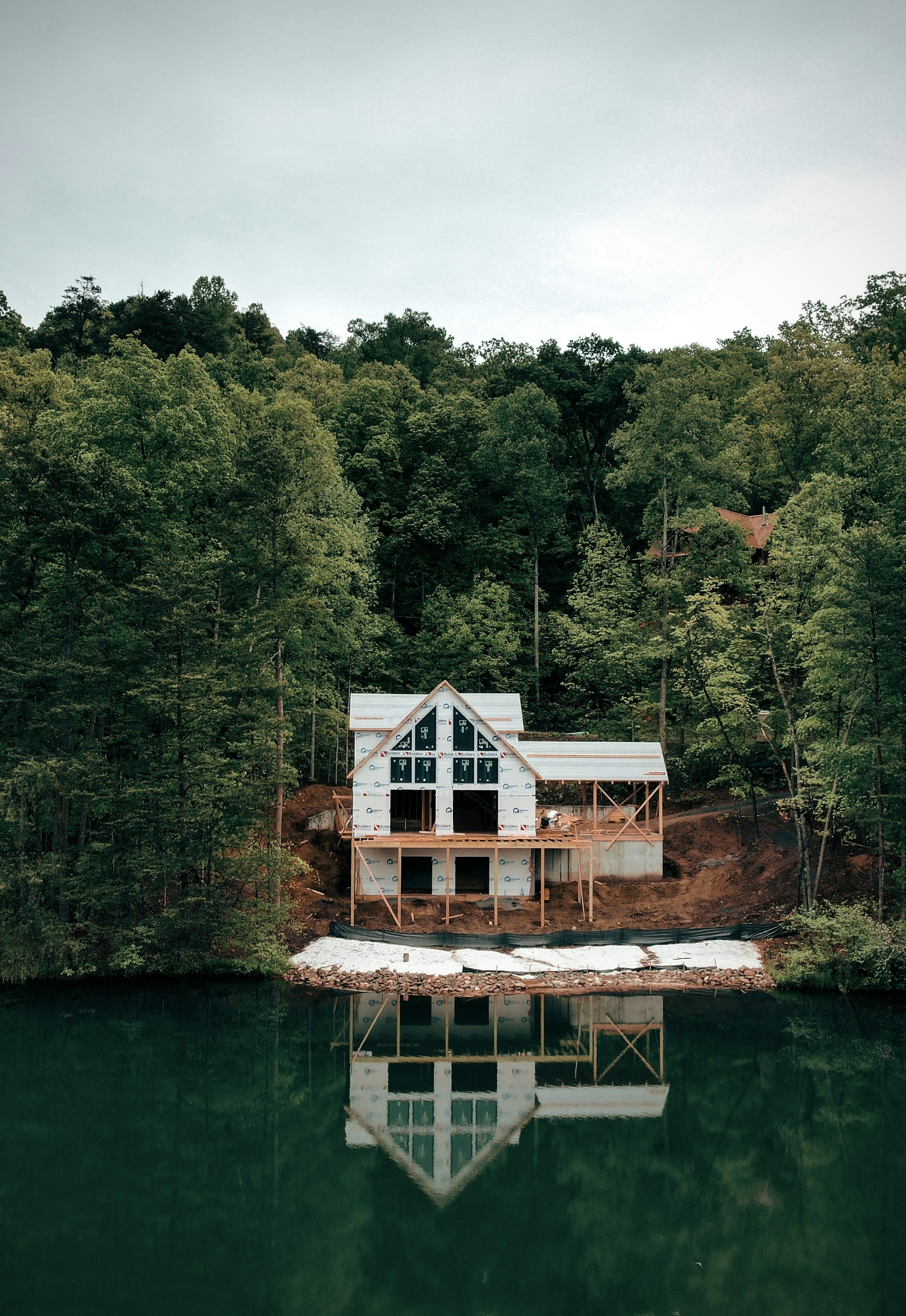 Una casa sentada en la cima de un lago junto a un bosque
