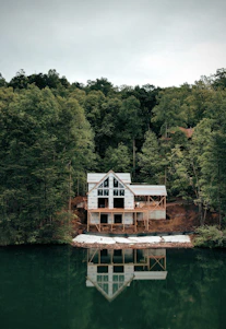 a house sitting on top of a lake next to a forest