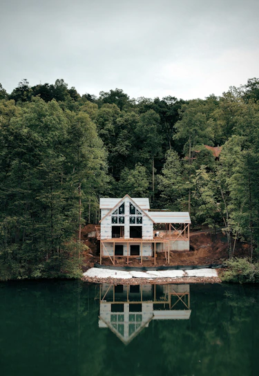 a house sitting on top of a lake next to a forest