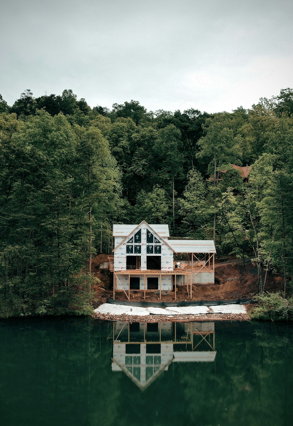 a house sitting on top of a lake next to a forest