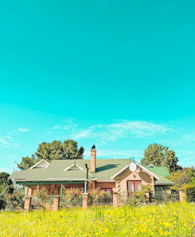 A charming countryside house surrounded by green fields and blue sky.