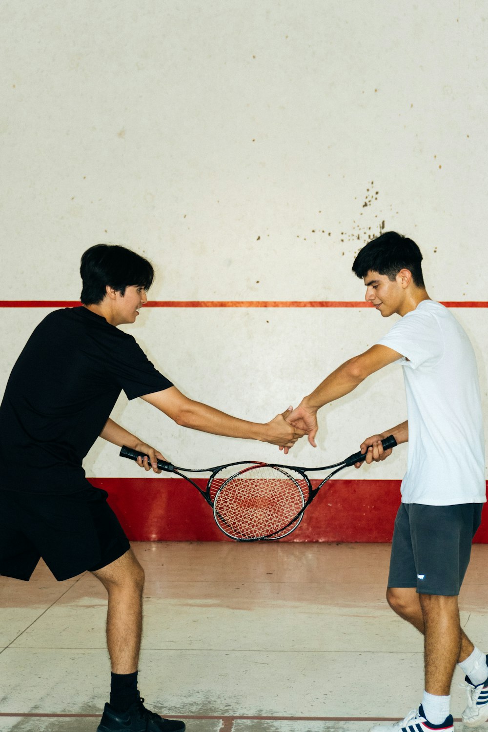 Deux jeunes hommes tenant des raquettes de tennis sur un court
