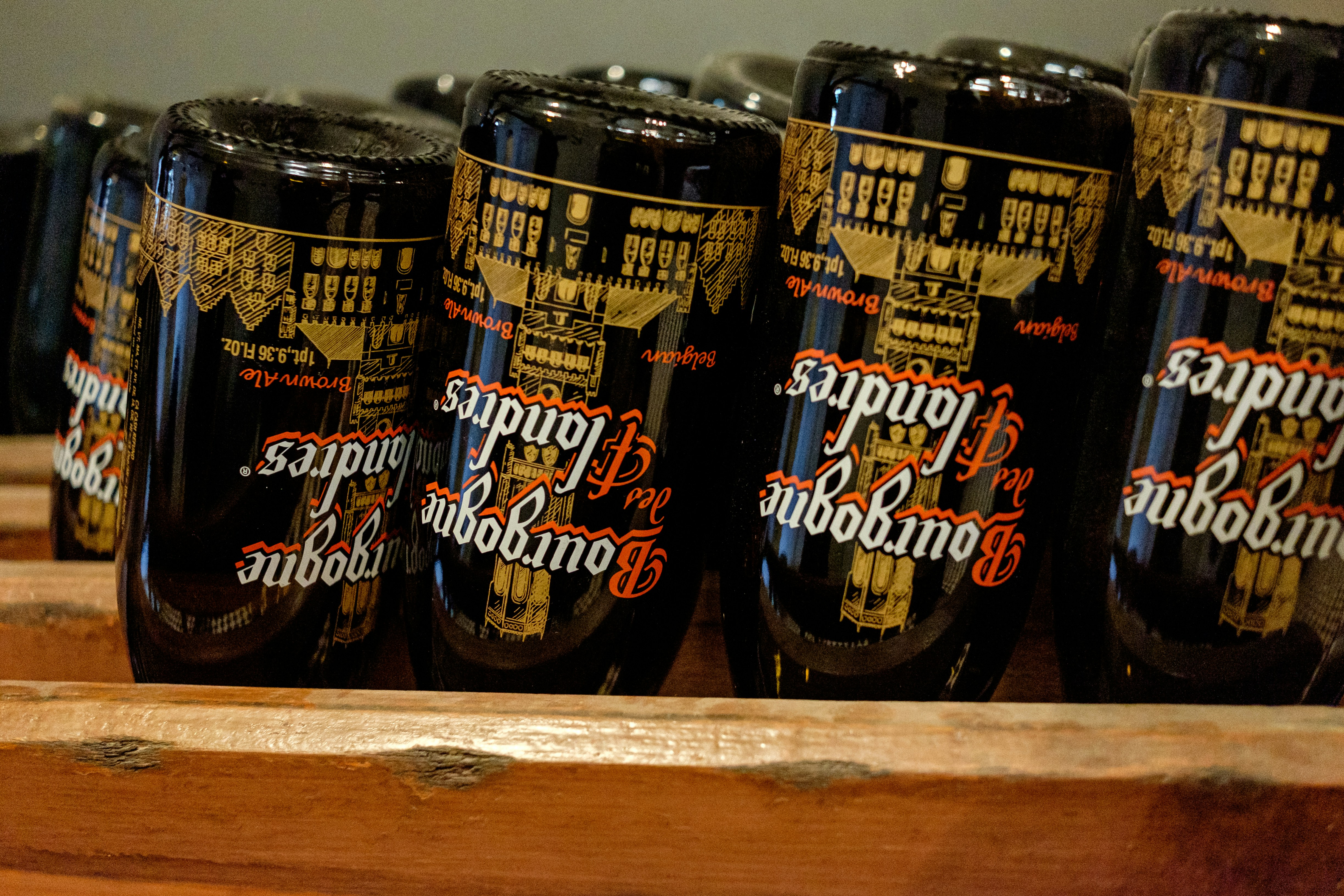 a row of beer bottles sitting on top of a wooden shelf