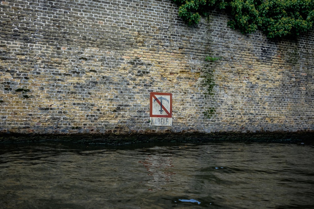 a no swimming sign on a brick wall