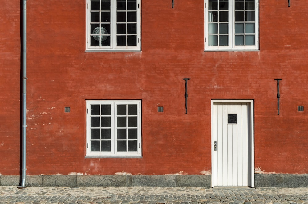 um edifício de tijolos vermelhos com três janelas e uma porta branca