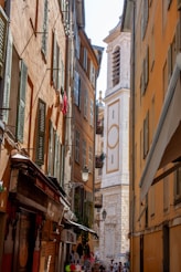 a narrow city street with a clock tower in the background