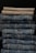 A neatly stacked collection of folded pants, with two khaki colored pants at the top followed by multiple layers of blue denim jeans below.