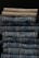 A neatly stacked collection of folded pants, with two khaki colored pants at the top followed by multiple layers of blue denim jeans below.
