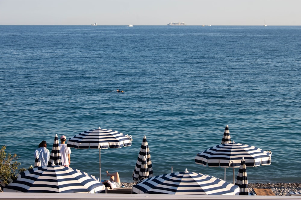 Eine Gruppe von Sonnenschirmen, die auf einem Strand neben dem Meer sitzen