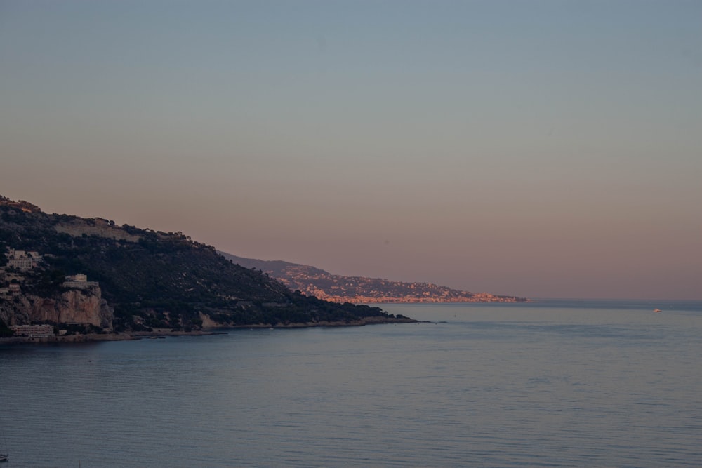 a body of water with a hill in the background