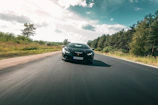 A modern black sports car with gold trim speeding along an empty highway.