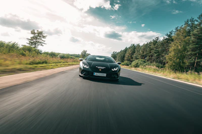 A modern black sports car with gold trim speeding along an empty highway.