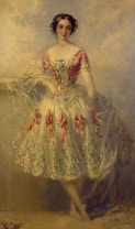 A woman in an elegant, ornate dress stands with a graceful pose. The dress features intricate patterns with red accents and a flowing, layered skirt. She has flowers in her hair and leans against a ledge, surrounded by a soft, blurred background that suggests a classical or romantic setting.