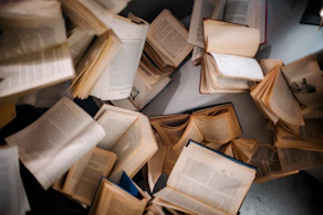 a pile of open books sitting on top of a table