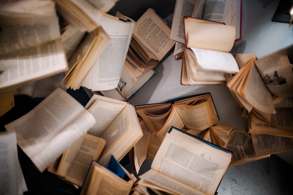 a pile of open books sitting on top of a table