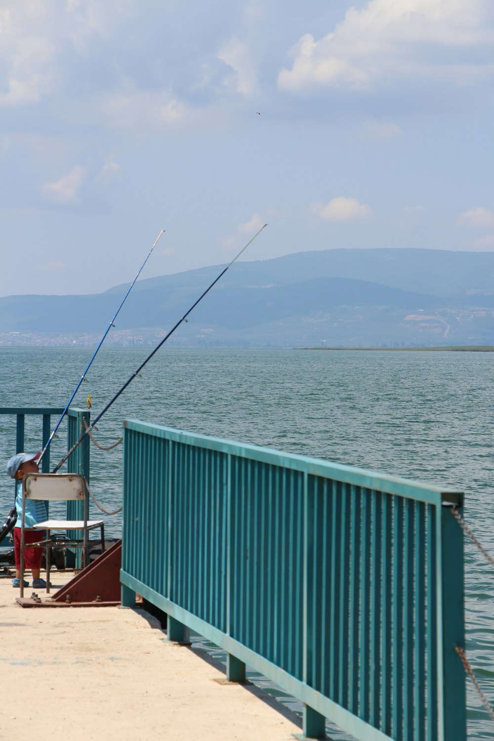 a man fishing on a pier next to the ocean