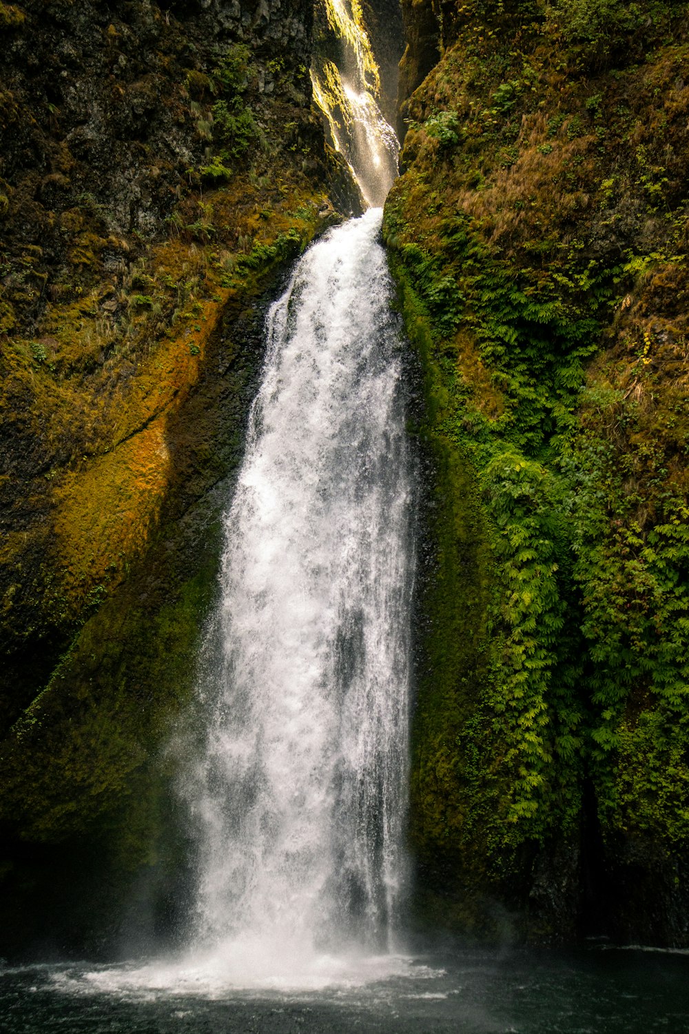 uma cachoeira com um homem parado na frente dela