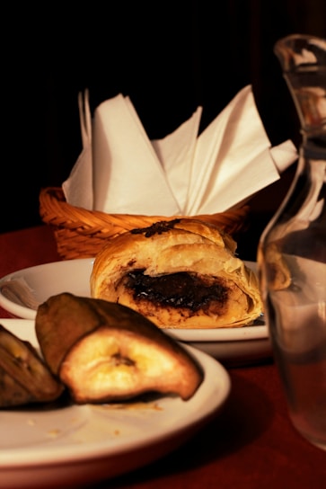 Close-up of golden crispy pastry filled with creamy banana and cheese filling on a rustic wooden table.