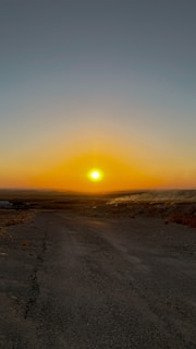 Sunset over a quiet open plot with a dirt road leading to it.