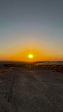Sunset over a quiet open plot with a dirt road leading to it.