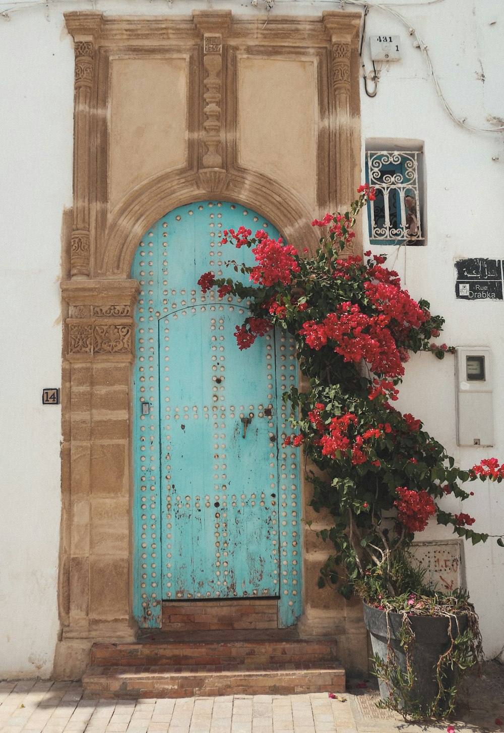 a blue door with red flowers in front of it