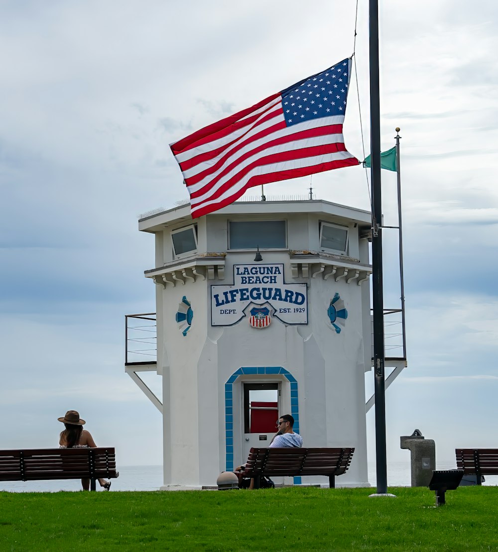 two people sitting on a bench in front of a lifeguard tower