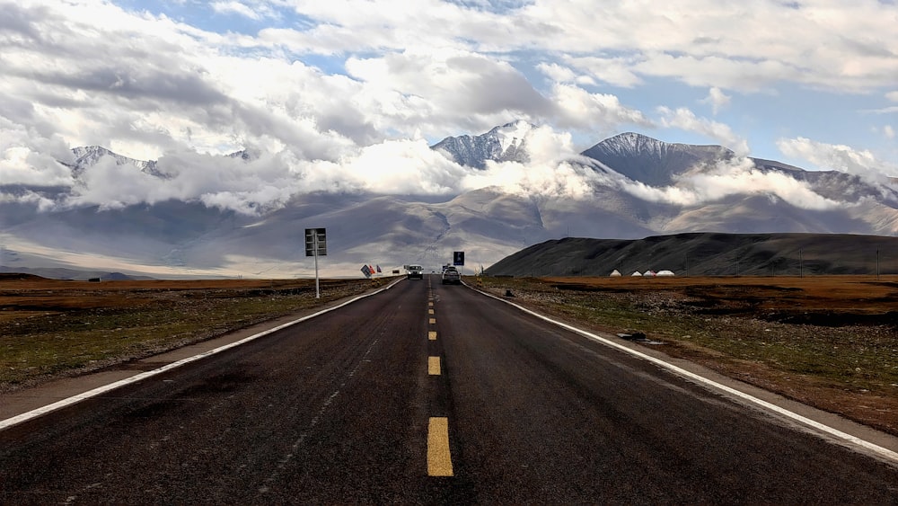 an empty road with mountains in the background