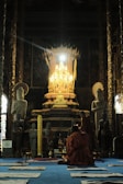 A serene scene of a Buddhist monk chanting inside a temple.