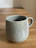 Handcrafted ceramic mug with warm morning light highlighting its texture.