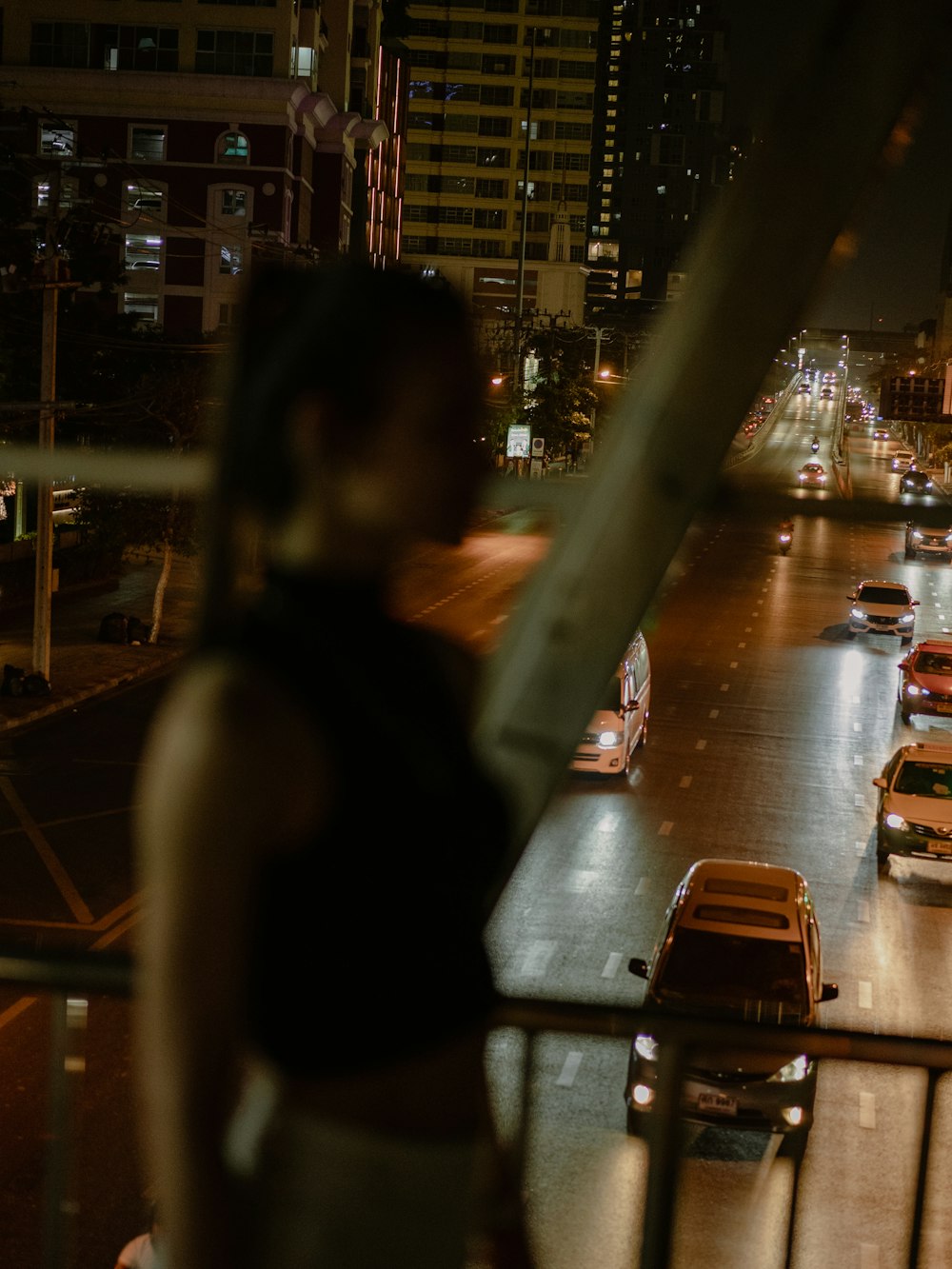 a woman standing on a balcony overlooking a city street at night