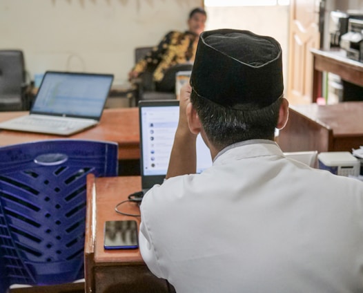 A professional translator working at a desk surrounded by research documents and a laptop.
