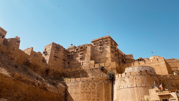 Ancient stone walls of Agra Fort standing tall against a clear blue sky.