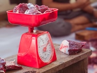 a red scale with meat on top of it