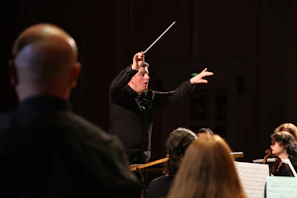 Close-up of a conductor’s hands holding a baton over sheet music