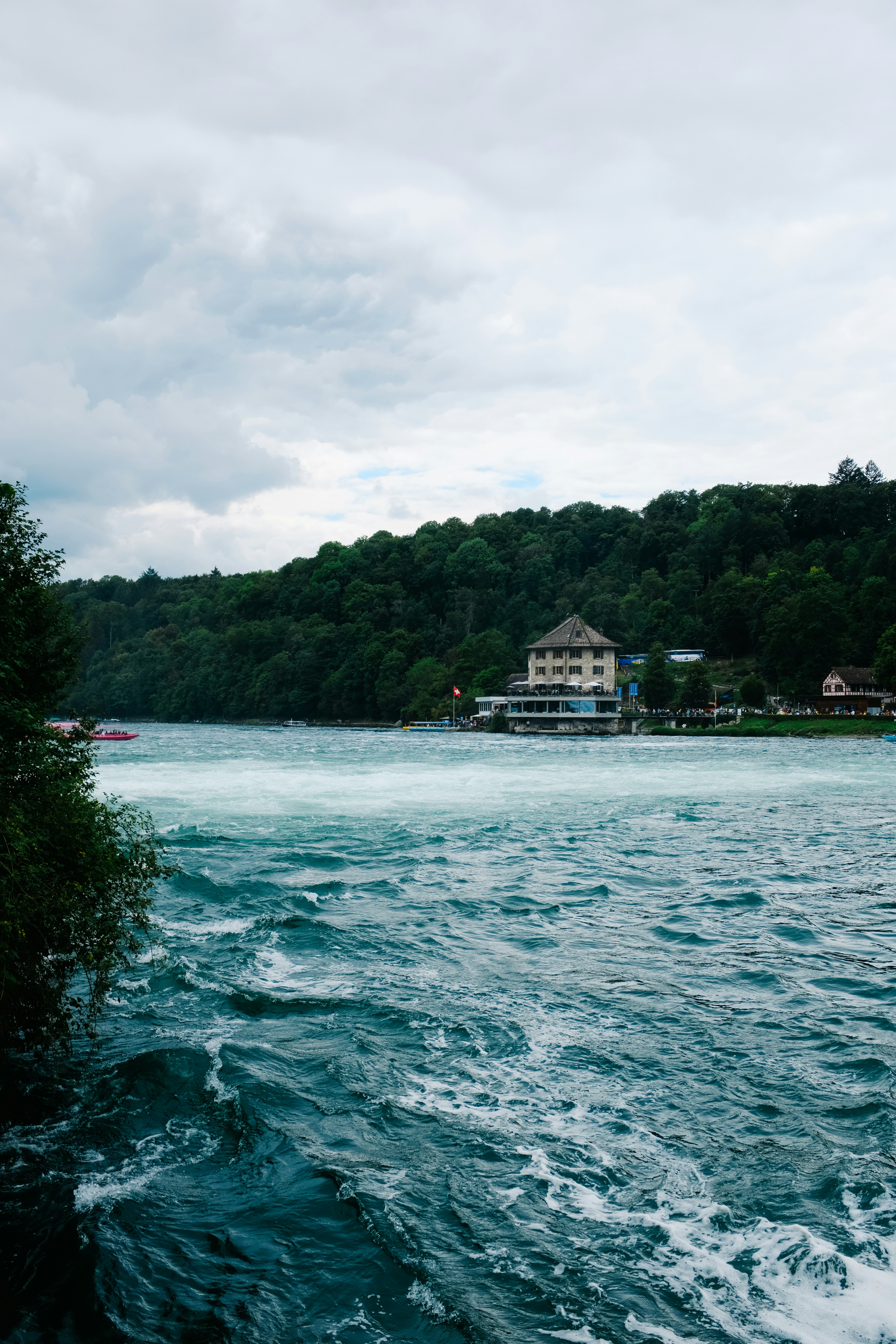 a large body of water with a house on a hill in the background