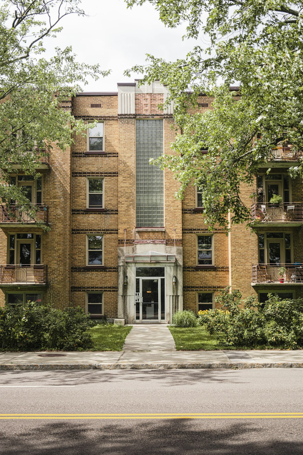 a tall brick building sitting next to a lush green park