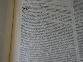 A close-up of a Bible open to a specific section, with text focused on Ezekiel chapter 20. The page displays verses about rebellion and judgment with bold headings.