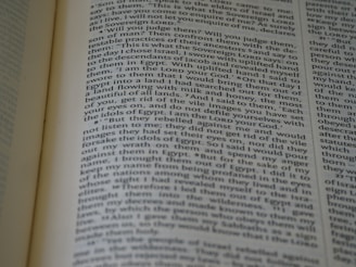 A close-up view of an open book with text on the pages. The text appears to be in paragraph format, possibly from a religious or historical book, and seems to be discussing narratives or instructions.