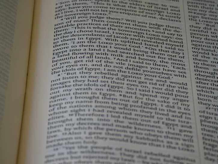 A close-up view of an open book with text on the pages. The text appears to be in paragraph format, possibly from a religious or historical book, and seems to be discussing narratives or instructions.