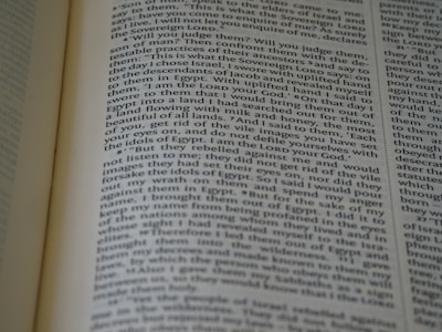 A close-up view of an open book with text on the pages. The text appears to be in paragraph format, possibly from a religious or historical book, and seems to be discussing narratives or instructions.