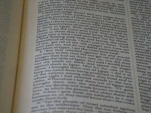 A close-up view of an open book with text on the pages. The text appears to be in paragraph format, possibly from a religious or historical book, and seems to be discussing narratives or instructions.