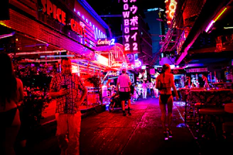 A lively nighttime street scene in Lyon with neon lights and people using their phones.