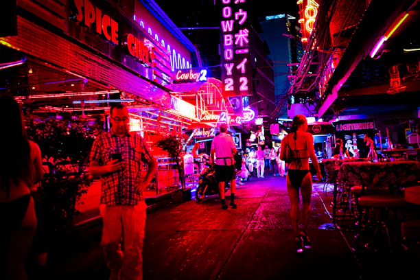A lively nighttime street scene in Lyon with neon lights and people using their phones.