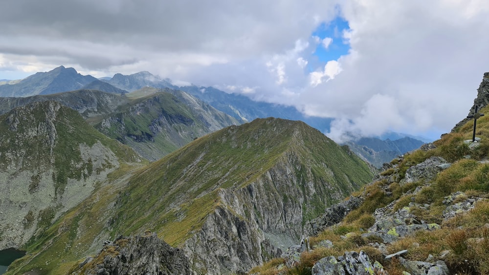 a man standing on top of a mountain next to a lush green hillside